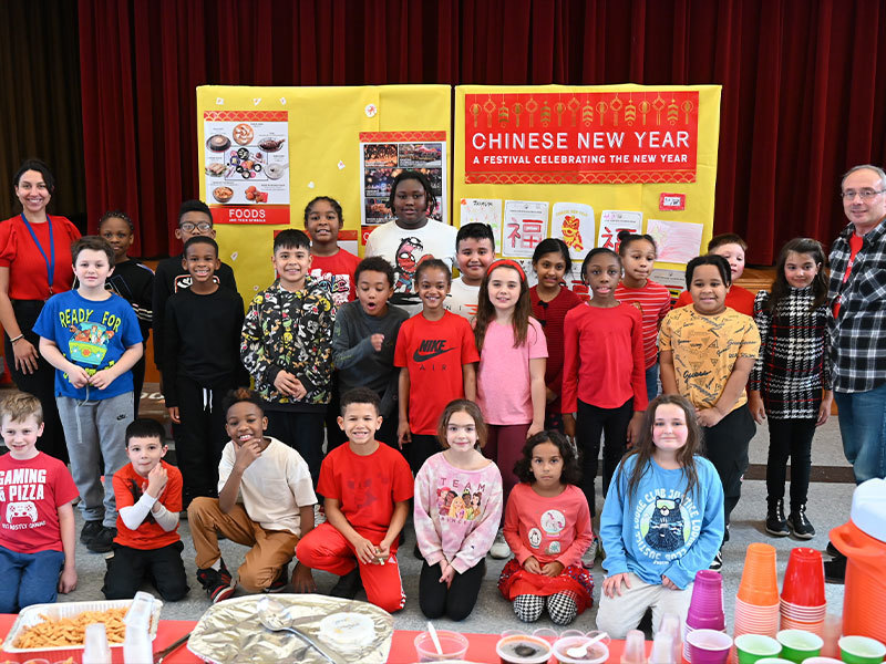 Students and teachers smiling while surrounded by Chinese New Year decorations