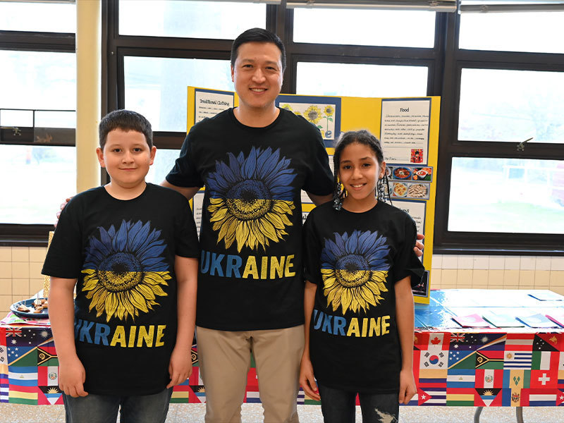 Three people wearing Ukraine t-shirts and smiling at the camera